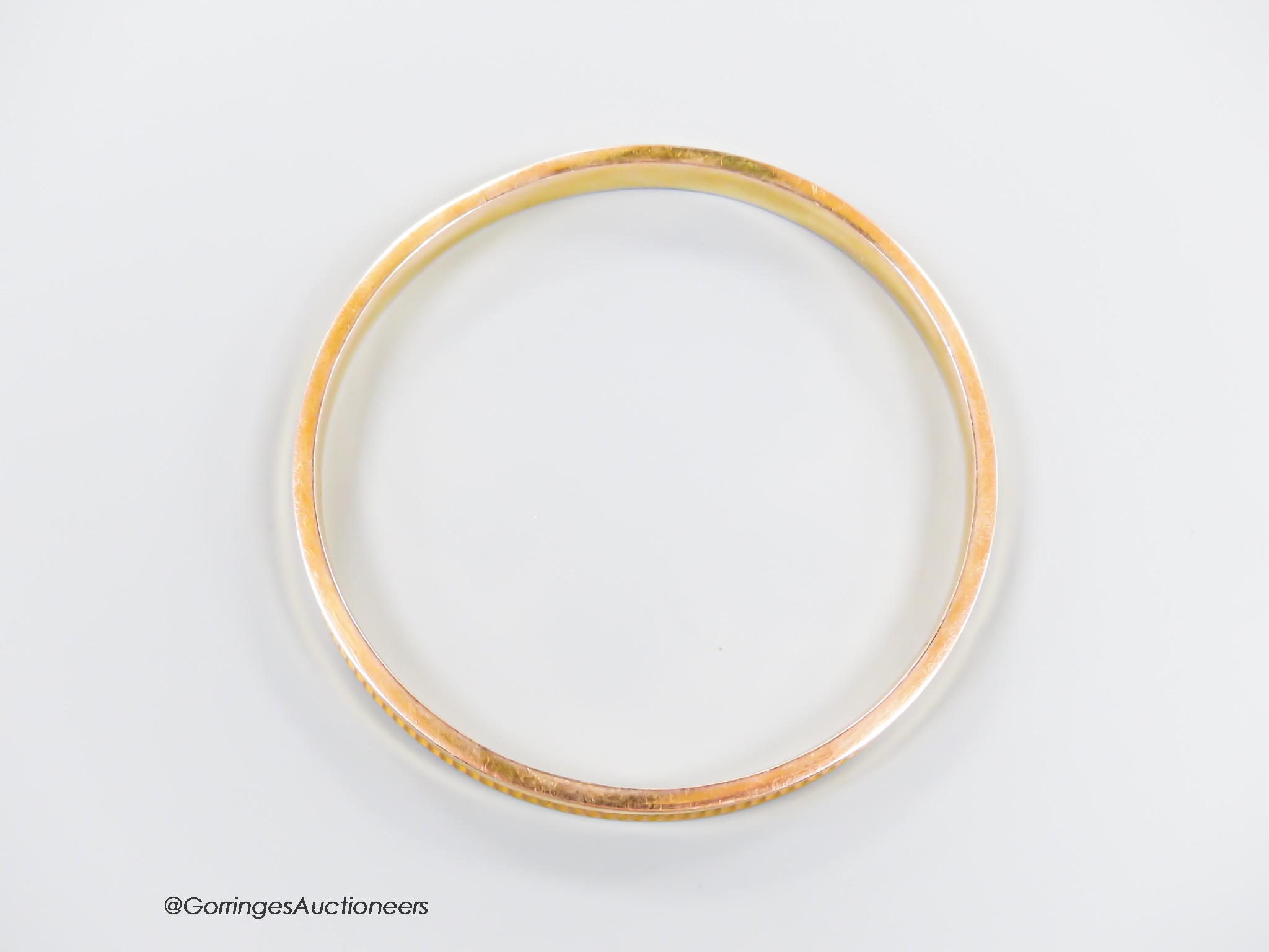 A 1930's engine turned 9ct gold bangle, interior diameter 73mm, 9 grams.